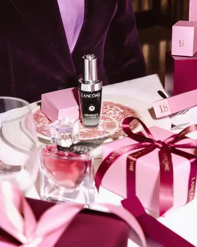 Kosmetyki Lancome i rożowe pudełka prezentowe ułożone na świątecznym stole.