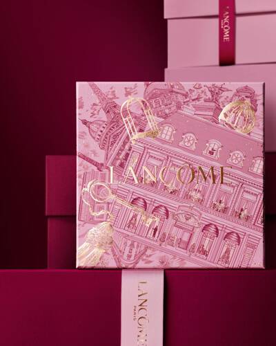 Elegancki stos rożowych i głęboko bordowych pudełek z Lancome, z centralnym pudełkiem ozdobionym złotymi paryskimi ilustracjami architektonicznymi.