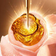 Złoty eliksir w kropli oleju na delikatnym płatku roży, emanowany blaskiem.