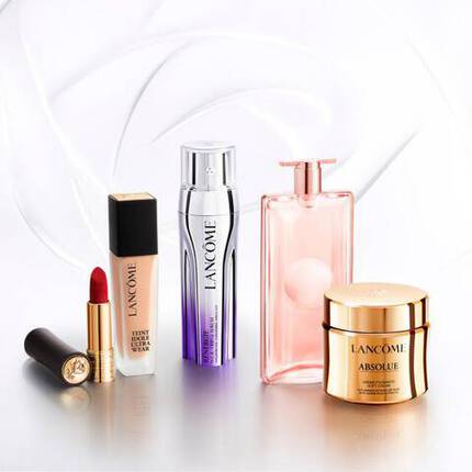 Zestaw kosmetykow marki Lancome, w tym podkład, pomadka, serum oraz kremy w eleganckim opakowaniu.