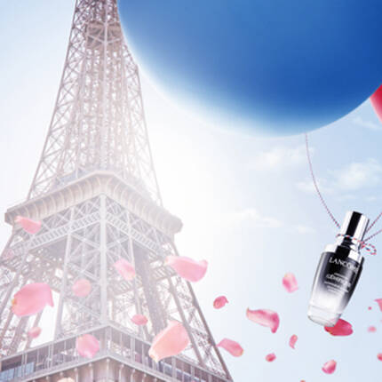 A vibrant scene featuring the Eiffel Tower, with red, white, and blue balloons floating nearby. In the foreground, a bottle of perfume is prominently displayed, surrounded by pink rose petals.
