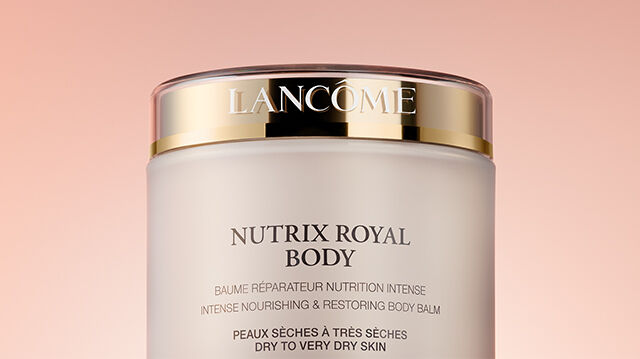 A close-up of a jar of Lancome Nutrix Royal Body cream against a soft, pink background.