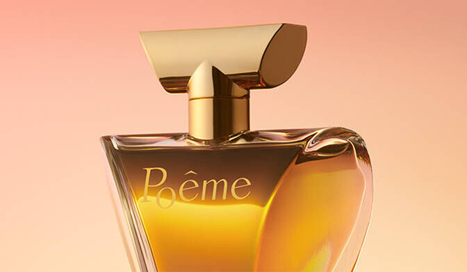 A close-up of a perfume bottle with an elegant design, featuring a gold cap and a clear glass body filled with a warm, amber-colored liquid. The label reads "Poeme." The background has a soft gradient from peach to light pink.