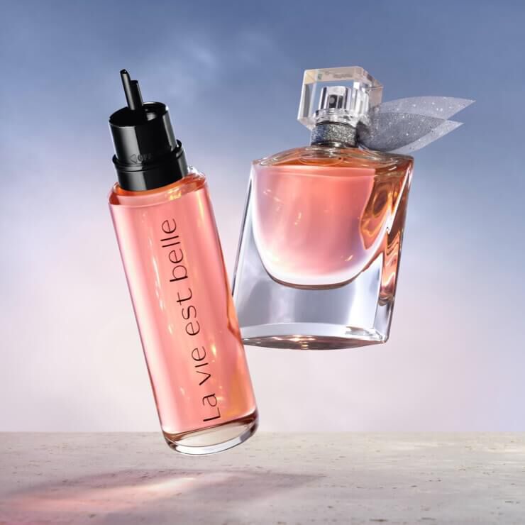 Dwa flakony perfum w rożowych odcieniach na tle nieba.