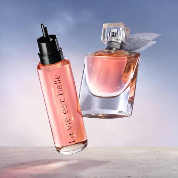 Dwa flakony perfum w rożowych odcieniach na tle nieba.