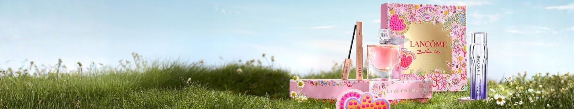 Świąteczne zestawy prezentowe Lancome w rożowych pudełkach w stylu vintage na tle ośnieżonych gor.