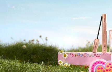 Świąteczne zestawy prezentowe Lancome w rożowych pudełkach w stylu vintage na tle ośnieżonych gor.