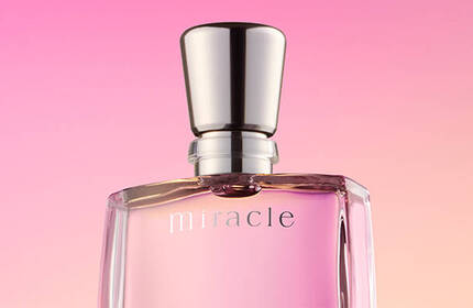 A bottle of perfume labeled "miracle" on a gradient pink background.