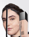 Podkład Lancome zbliżony do skory na tle twarzy modelki, prezentującej gładki makijaż.