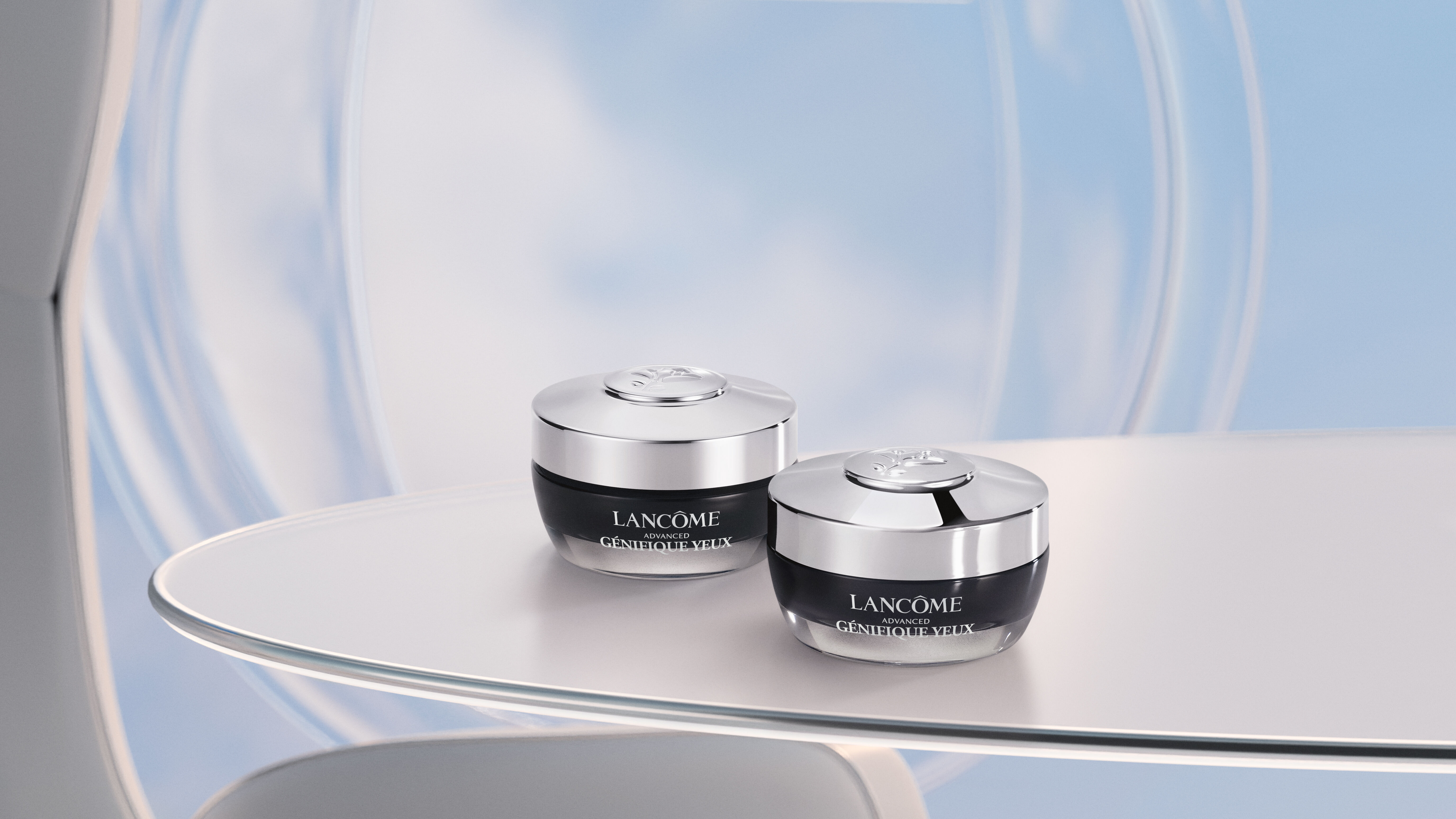 Two elegant jars of skincare cream are displayed on a sleek, modern table, set against a soft blue background that suggests a serene atmosphere.