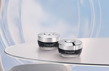 Two elegant jars of skincare cream are displayed on a sleek, modern table, set against a soft blue background that suggests a serene atmosphere.