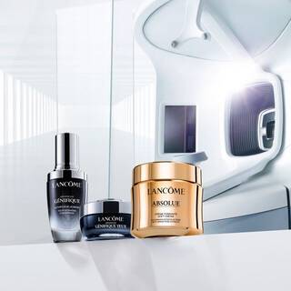 Trzy produkty do pielęgnacji skory marki Lancome, w tym serum i krem, ustawione na eleganckim tle.