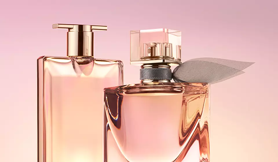Two elegant perfume bottles are displayed against a soft pink background, showcasing their graceful shapes and subtle colors.