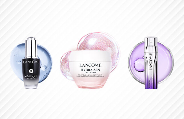 Three skincare products from Lancome displayed against a textured light background: a serum in a dark bottle, a cream in a pink jar, and a treatment in a silver tube.
