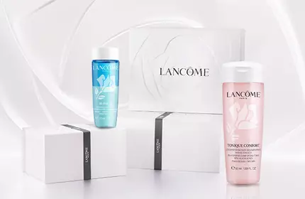 A collection of Lancome skincare products displayed on a soft, wave-like background. The products include two bottles, one blue and one pink, alongside a white box with the Lancome logo.