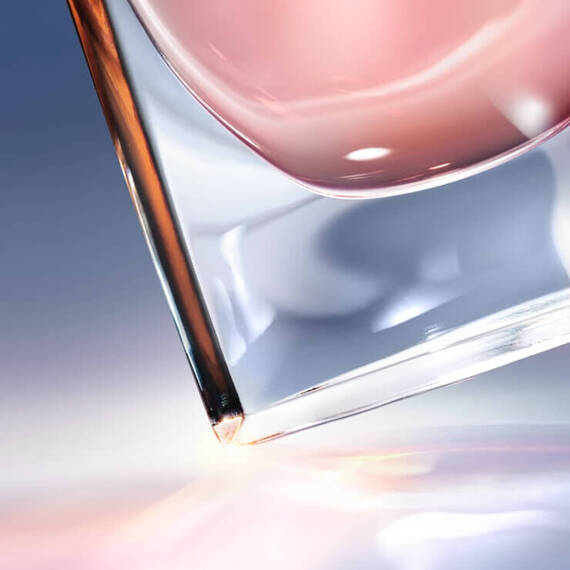 Szkło z rożowym płynem w lekko przechylonej pozycji na gładkiej powierzchni.