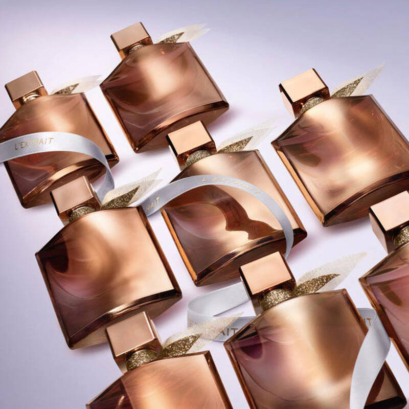 Изображение на няколко парфюма с розови бутилки, разположени в редица, с лъскави завязки.