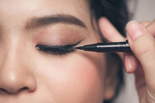 Kobieta wykonująca kreskę na oku eyelinerem w pisaku